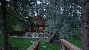 A rustic cabin surrounded by dense forest, with a stone pathway leading to the entrance.