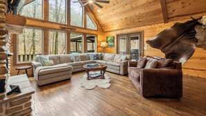 Ein geräumiges Blockhaus-Interieur mit einer großen Eckcouch, einer zusätzlichen Couch und einem Couchtisch.