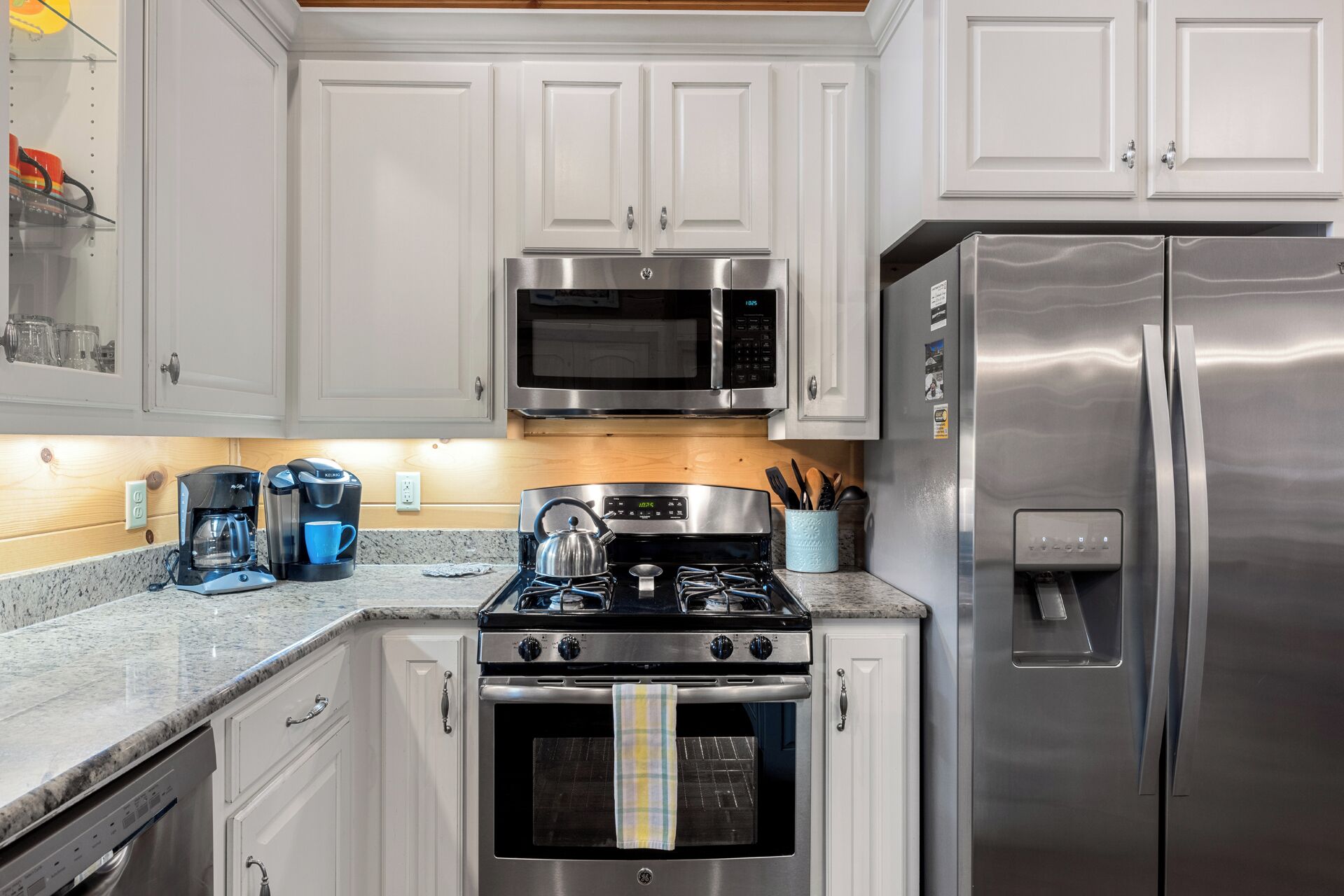 A kitchen with white cabinets, a stainless steel stove, a microwave, and a refrigerator.