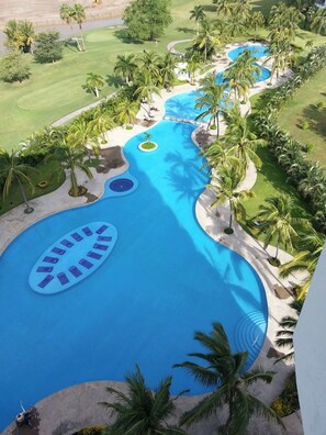 Ein Resort mit großem Pool, Palmen und einem Golfplatz.