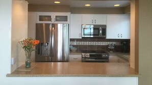 A kitchen with stainless steel appliances, white cabinets, and a tiled backsplash. - A Romantic Getaway at the "White Water Cove" At Ocean View Rainbow Rock!  (Brookings)