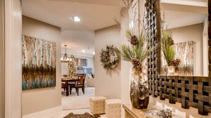 Un intérieur moderne comprenant un coin repas, un grand vase décoratif et un panneau mural tissé.