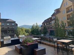 Un patio exterior con una parrilla, zona de estar y vistas a la montaña.