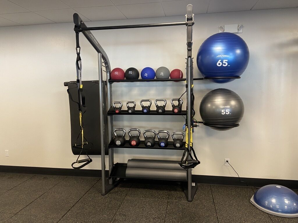 Academia com barra para puxar, halteres e bolas de exercício.
