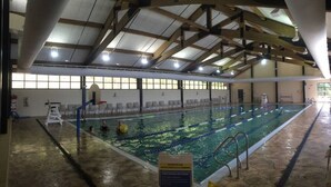 An indoor swimming pool with clear lanes, a lifeguard chair, and a sign indicating pool rules. - Splendid Home Away From Home -5 Bdr- with Hot Tub (Galena)