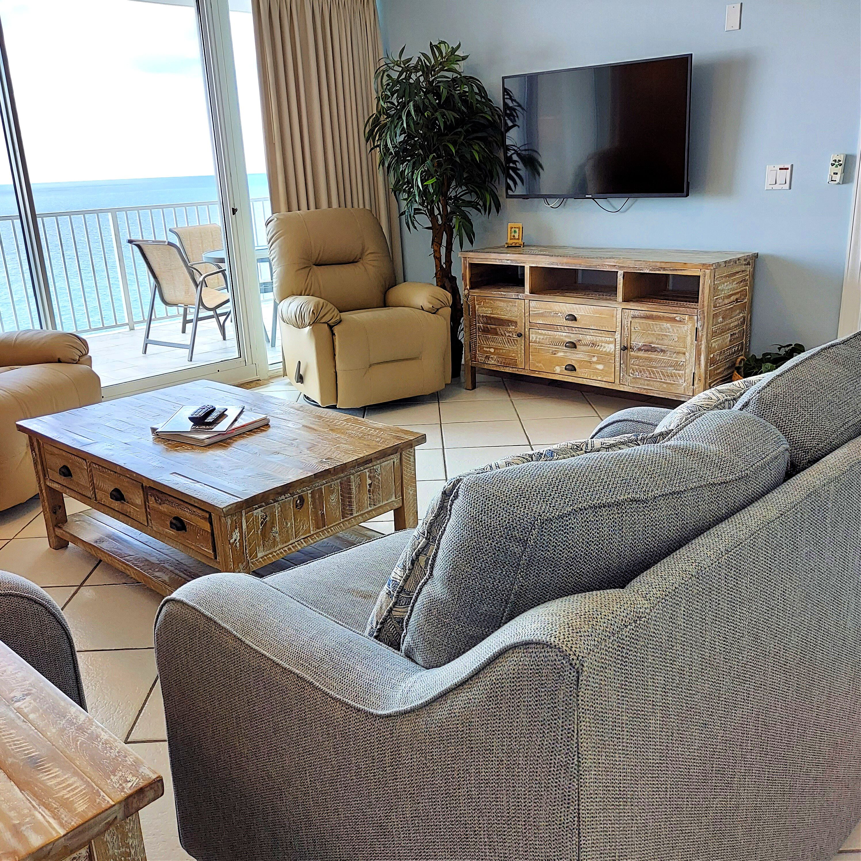Ein Wohnzimmer mit einer Couch, einem Holztisch, einem Fernseher und einer Pflanze.