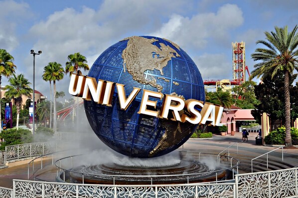 A large globe with the word "UNIVERSAL" prominently displayed, surrounded by a fountain and palm trees.