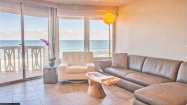 Een moderne woonkamer met uitzicht op de oceaan, een plafondventilator en een bank.