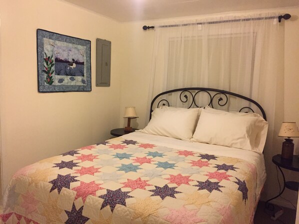 A neatly made bed with a star-patterned quilt, a bedside lamp, and a painting on the wall. - Historic Home
Comfort, Convenience, and Views! (Homer)