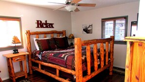 A wooden bed with a headboard, a small bedside table, a rug, and a ceiling fan. - Cozy 2-Cabin Retreat Near RMNP - Estes Park License #3051 (Estes Park)