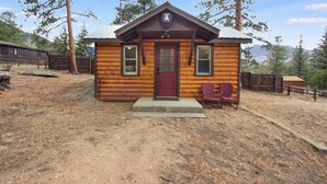 A small log cabin with a red door, two windows, and a porch. - Cozy 2-Cabin Retreat Near RMNP - Estes Park License #3051 (Estes Park)