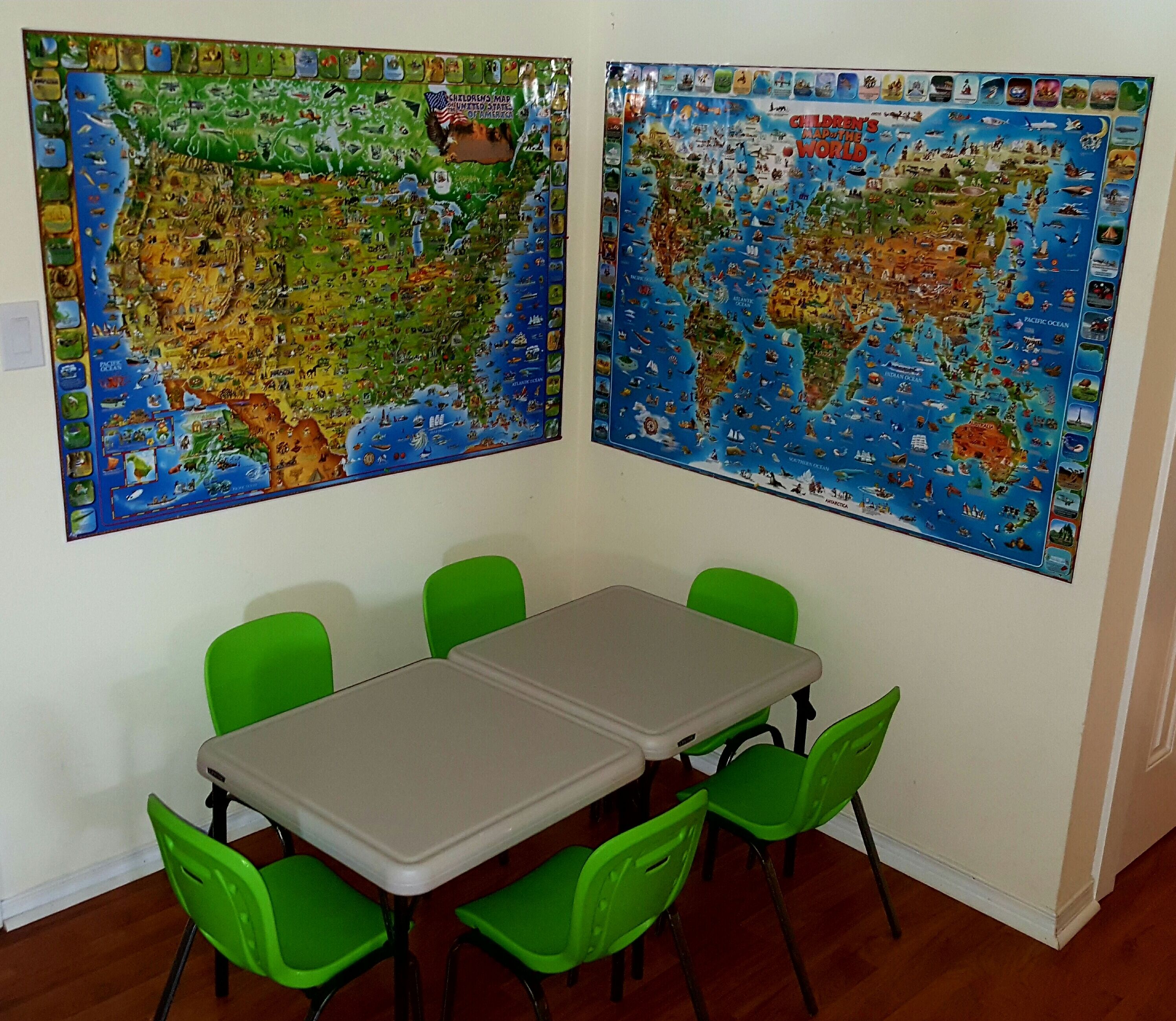 A room with a table and four green chairs, two large educational posters on the walls, and a whiteboard.