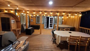 A cozy wooden interior with a dining area, a fireplace, and string lights.