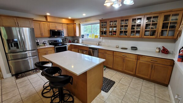 A modern kitchen with stainless steel appliances, wooden cabinets, and a central island with bar stools. - LARGE FAMILIES REUNIONS, ELOPE, CORPORATIONS MEETINGS & MORE (Snoqualmie Pass)