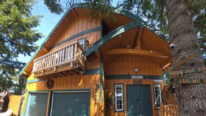 A wooden cabin with a balcony, two garage doors, and a welcome sign.