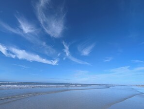 Ein Strand mit blauem Himmel und sanften Wellen.