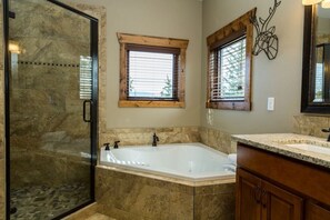 A bathroom with a large bathtub, a shower area, and wooden window frames. - Spacious mountain condo. Awesome views, Jacuzzi Tub. (Estes Park)