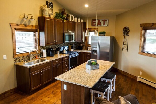 A kitchen with wooden cabinets, a granite countertop island, stainless steel appliances, and a windmill decoration. - Spacious mountain condo. Awesome views, Jacuzzi Tub. (Estes Park)