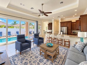 A spacious living area with a pool, a ceiling fan, and a kitchen with wooden cabinets. -  Best Value In Naples Grand luxury 3 Bdrm Pool Spa Walk Bike To Gulf Spotless (Naples)