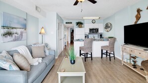A modern living room with a sofa, a coffee table, a TV, and a ceiling fan.