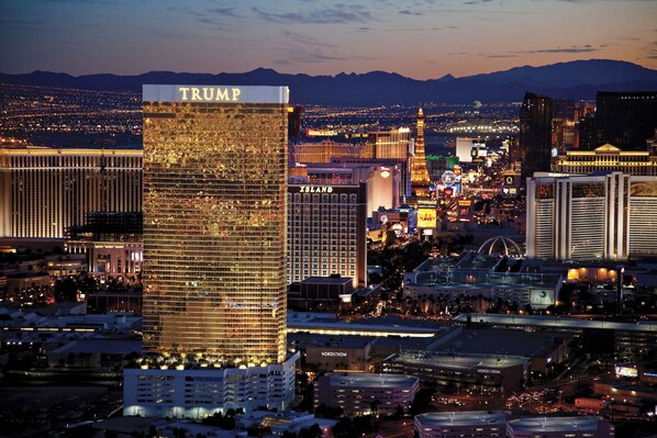 A high-rise hotel with a prominent 'TRUMP' sign at the top, surrounded by other buildings and city lights.