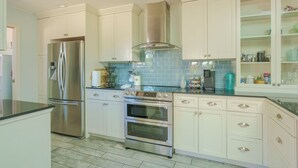 A kitchen with white cabinets, stainless steel appliances, and a tiled backsplash.