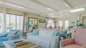 A spacious living room with a large window, a dining area, and a kitchen.