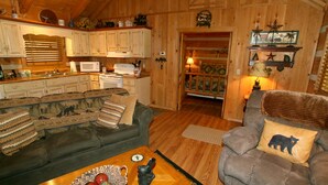 A cozy cabin interior with a dining area, kitchen, and seating space. - Real Log Cabin. Pet Friendly, fenced yard! Only 5 Min to Pigeon Forge (Sevierville)