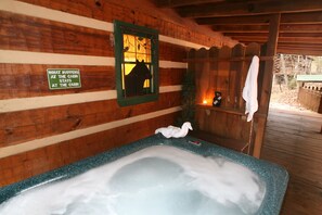 Ein Holzblockhaus-Interieur mit Whirlpool, einem Schild mit der Aufschrift 'Was im Blockhaus geschieht, bleibt im Blockhaus' und einem Fenster mit der Silhouette eines Pferdes.
