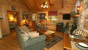 A cozy log cabin interior with a sofa, dining table, and fireplace. - Real Log Cabin. Pet Friendly, fenced yard! Only 5 Min to Pigeon Forge (Sevierville)