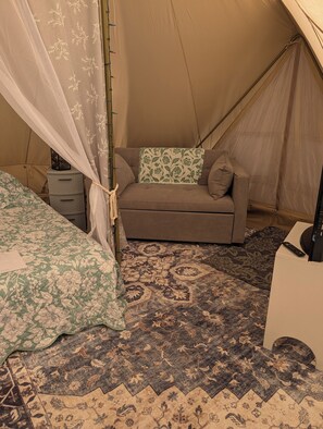 A tent with a sofa, a bed, and a rug.