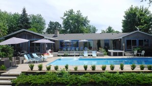 Un espace piscine équipé de chaises longues, de parasols et d’un jacuzzi.