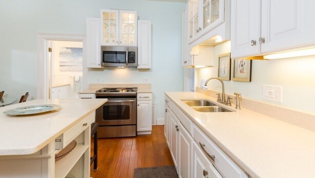 A modern kitchen with white cabinetry, stainless steel appliances, and a central island.
