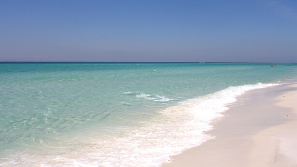 A beach with clear turquoise water and white sand.