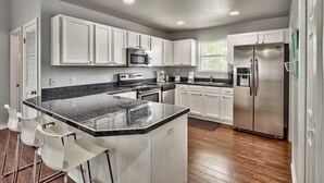 A modern kitchen with white cabinets, stainless steel appliances, and a granite countertop.