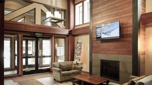 A lobby with a fireplace, seating area, and a television mounted on the wall.