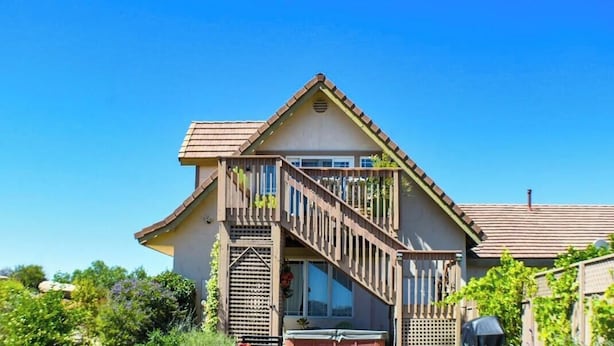 A two-story house with a balcony, a patio with outdoor furniture, and a garden. - San Diego Country Barndominium, Mountain Views, Spa, Deck, & More. (Valley Center)