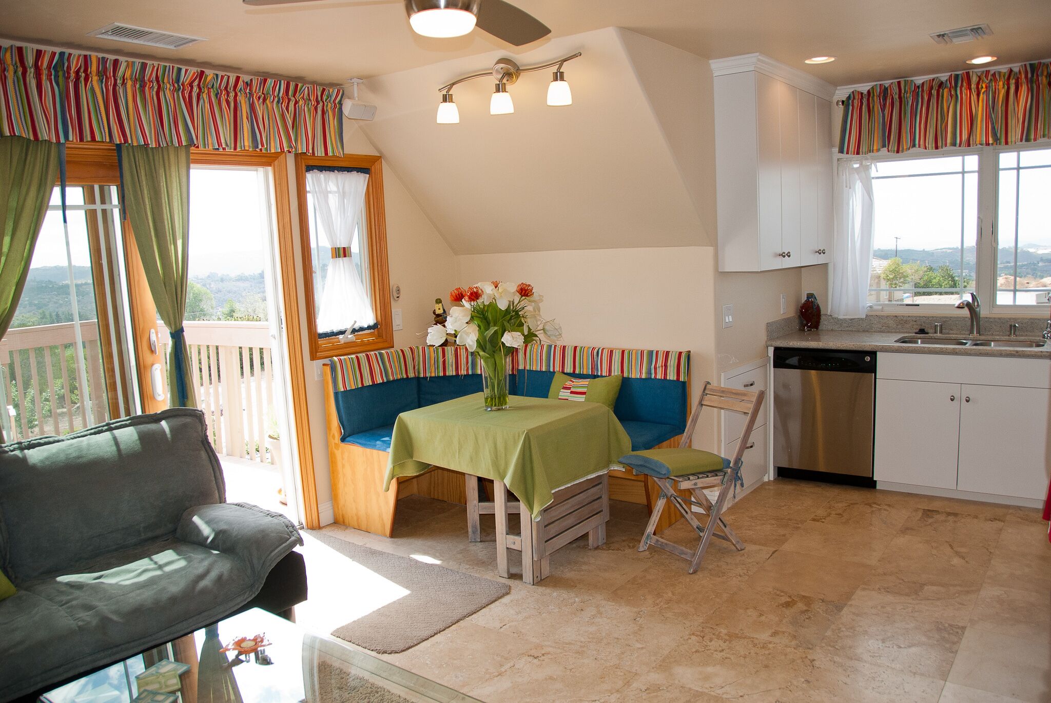 Une cuisine avec un coin repas, une vue sur l’extérieur et un ventilateur de plafond.
