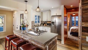 Una cocina moderna con una isla central, electrodomésticos de acero inoxidable e iluminación colgante.