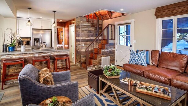 Un espacio habitable moderno con cocina, una escalera y una zona de estar.