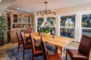 A dining area with a wooden table, leather chairs, and a chandelier.