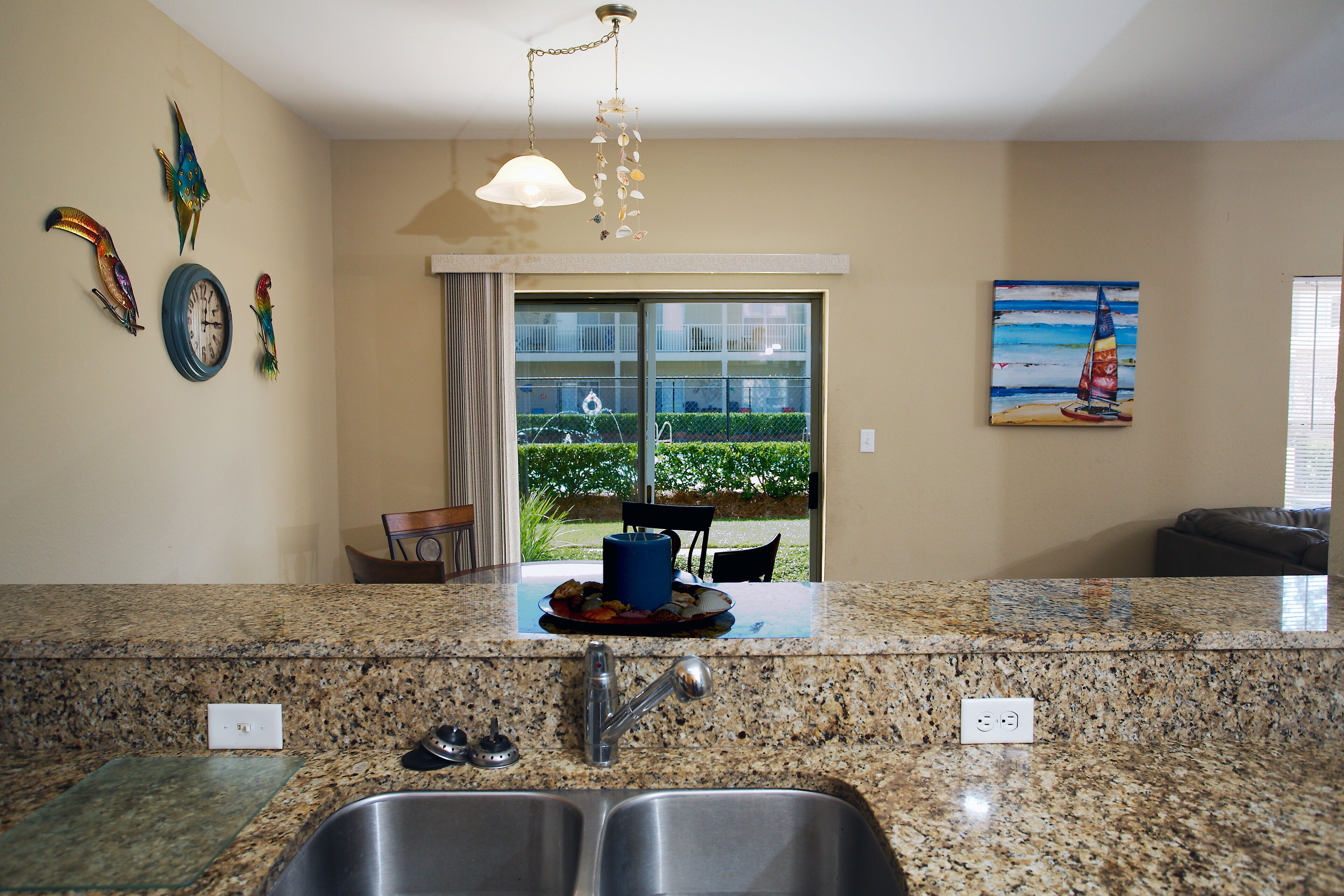 A kitchen with granite countertops, a double sink, and a dining area with a table and chairs.
