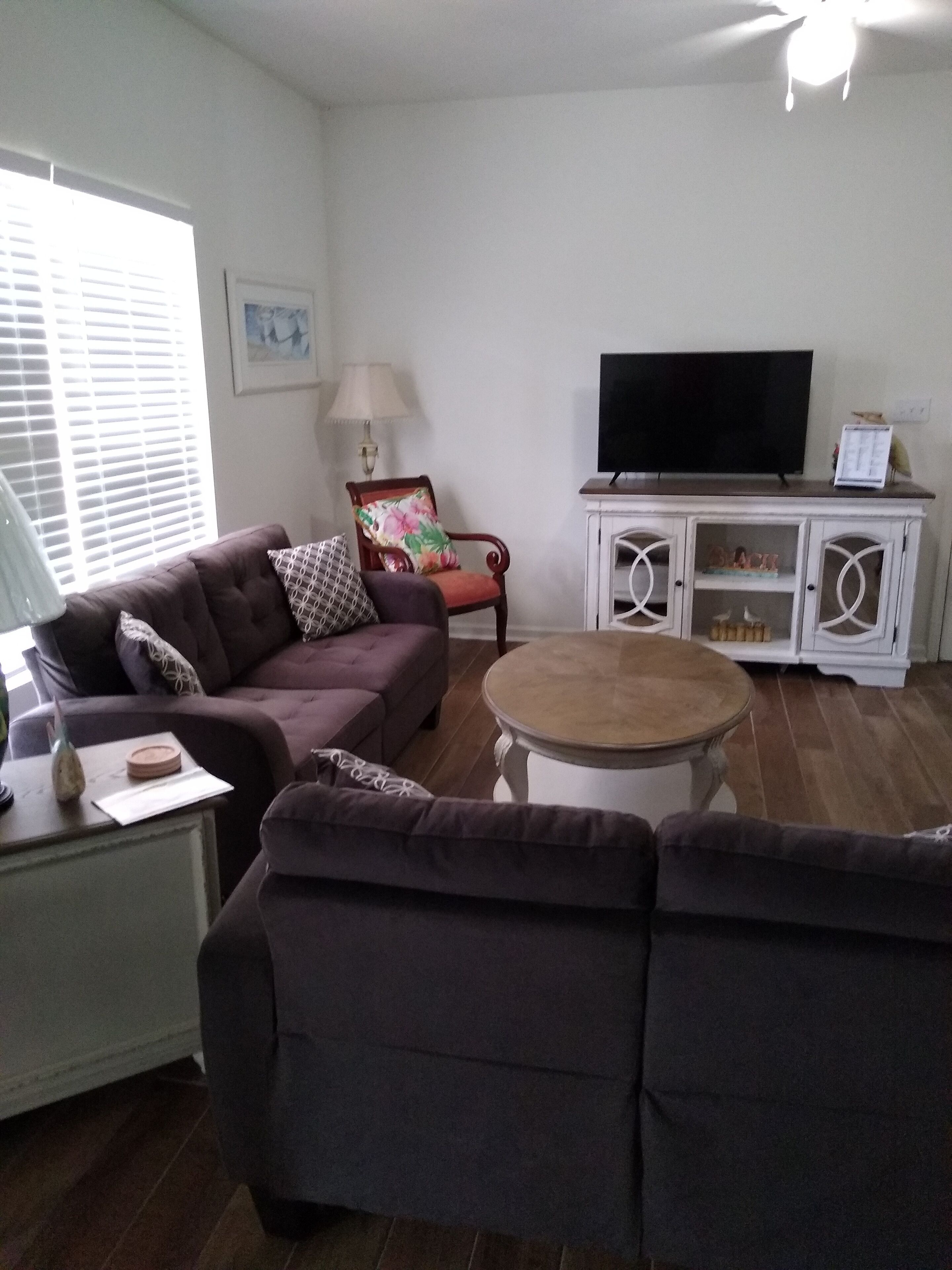 Una sala de estar con sofá, mesa de centro, televisor y aparador con objetos decorativos.