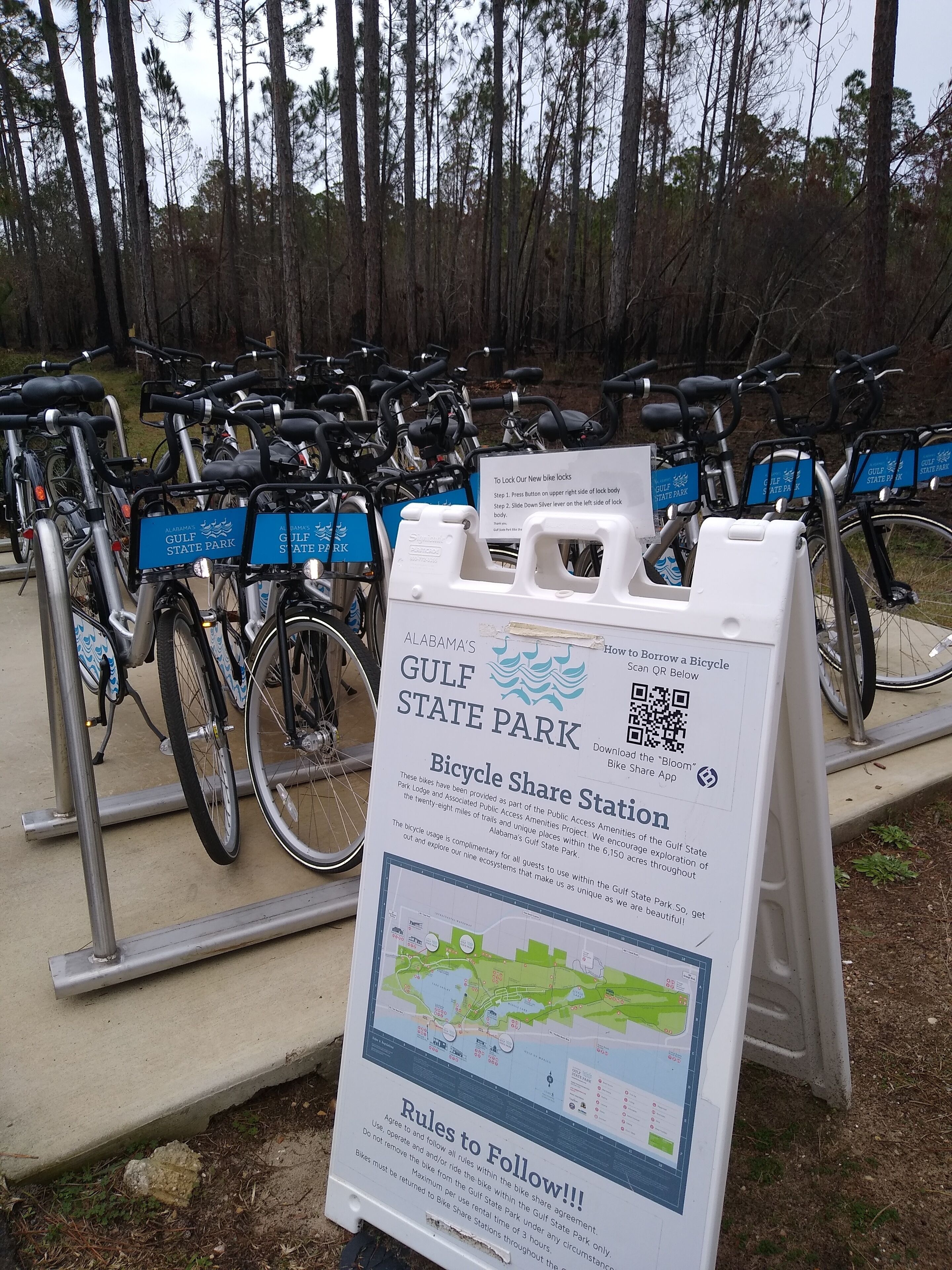 Een fietsdeelfaciliteit met een bord waarop regels en een kaart van het park staan.