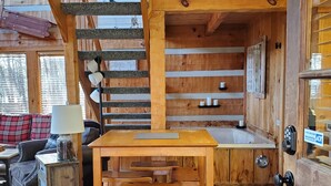 A wooden interior with a dining area, a staircase, and a view of the outside.