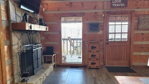 A cozy cabin interior with a stone fireplace, wooden walls, and a sign that reads "LIVE LOVE TRAVEL".