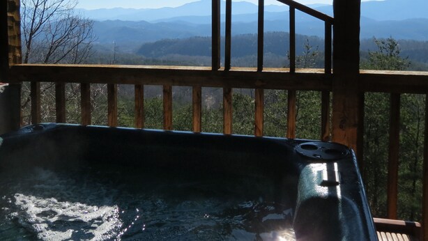 A hot tub on a wooden deck with a view of mountains.