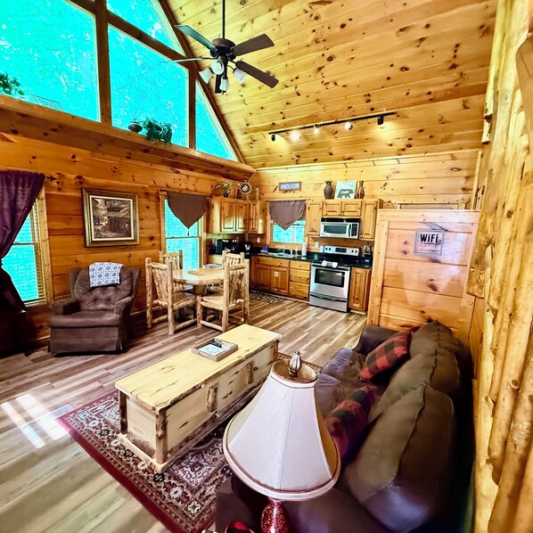 A cabin interior with a dining area, kitchen, and a sofa.