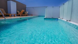 Een zwembad met helderblauw water, omringd door ligbedden en een modern gevelontwerp.
