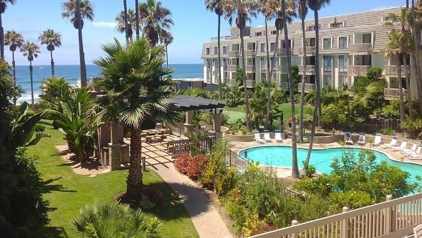 Un hôtel doté d’une piscine, de palmiers et offrant une vue sur l’océan.